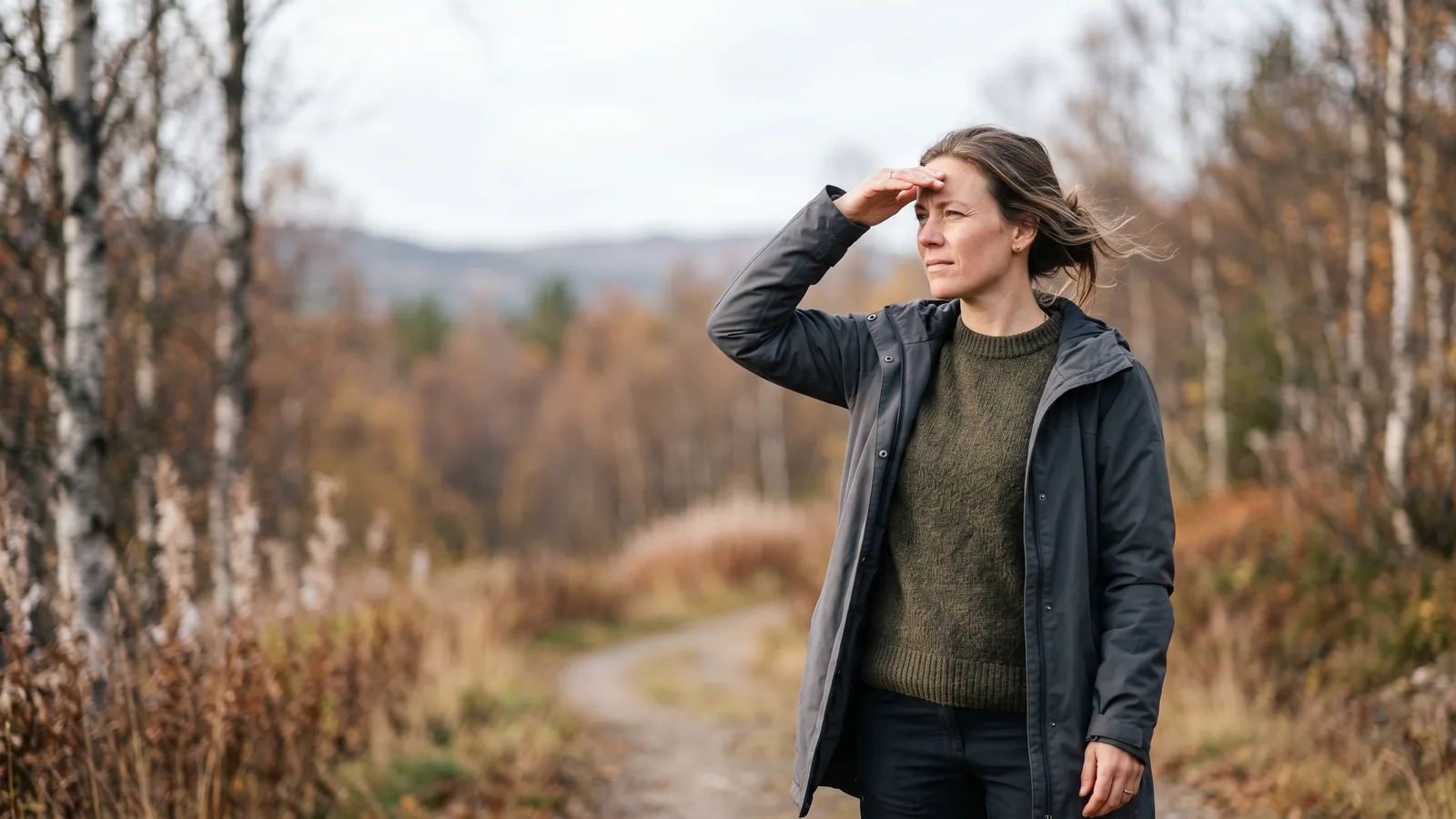 En person som kniper øynene sammen og holder en hånd opp mot skarpt lys gjennom et vindu, et typisk uttrykk for lysømfintlige øyne