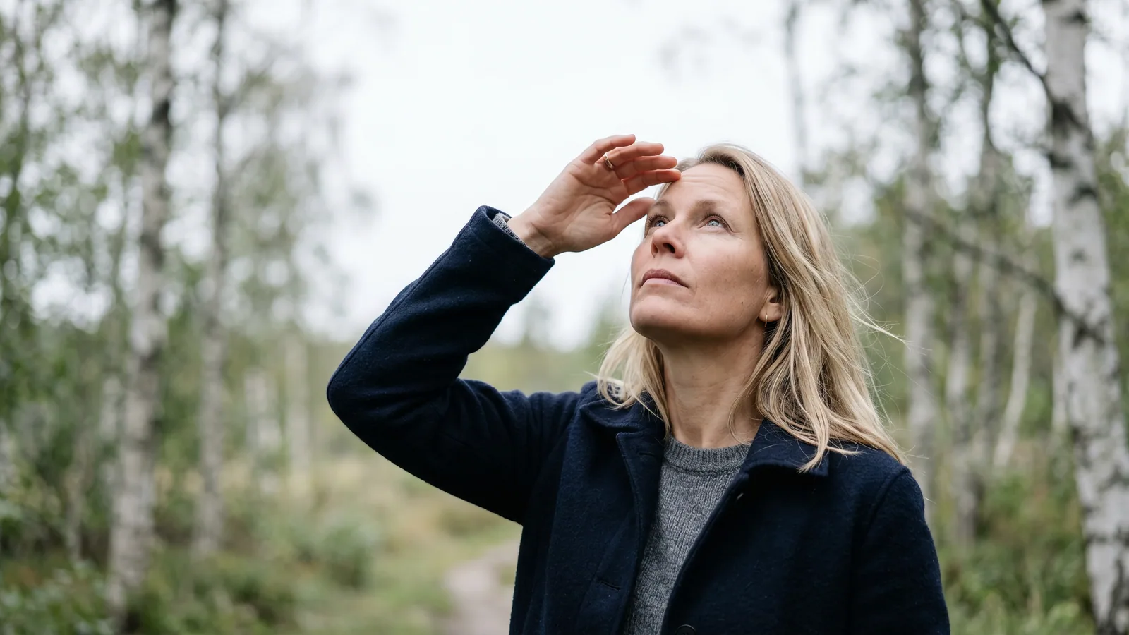 En kvinne ser opp mot en lys, jevn himmel og følger med blikket noe som svever i synsfeltet.