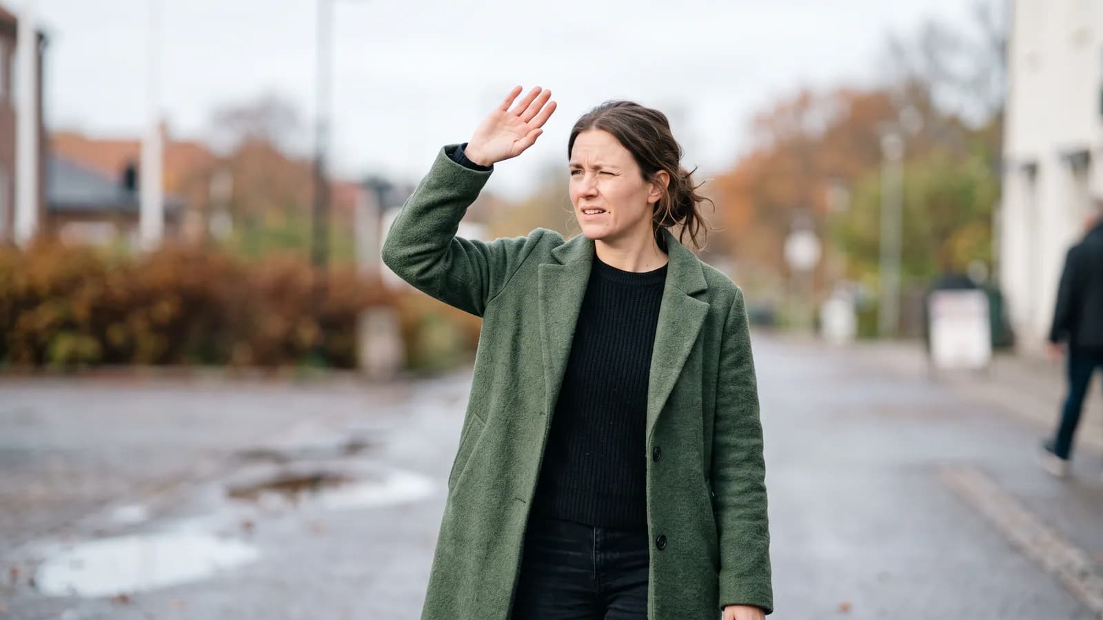 En person som kniper øynene sammen og holder en hånd opp mot skarpt lys gjennom et vindu, et typisk uttrykk for lysømfintlige øyne